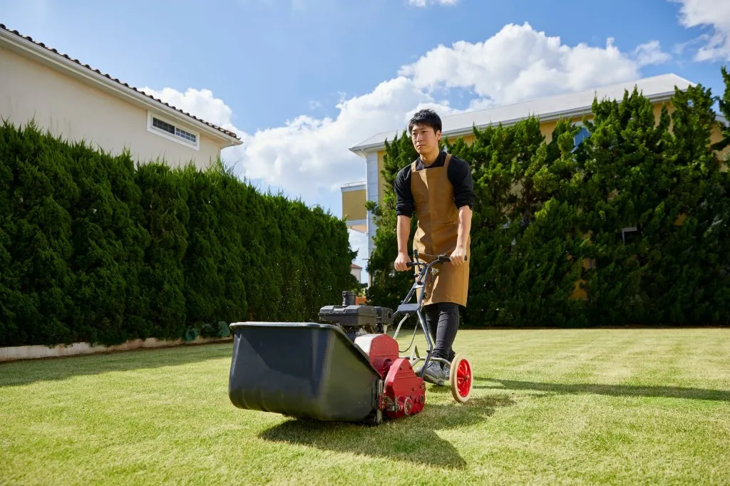 Landscaper mowing a lawn in front of a suburban home